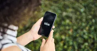 Woman looks at the Blink mobile app on a smartphone